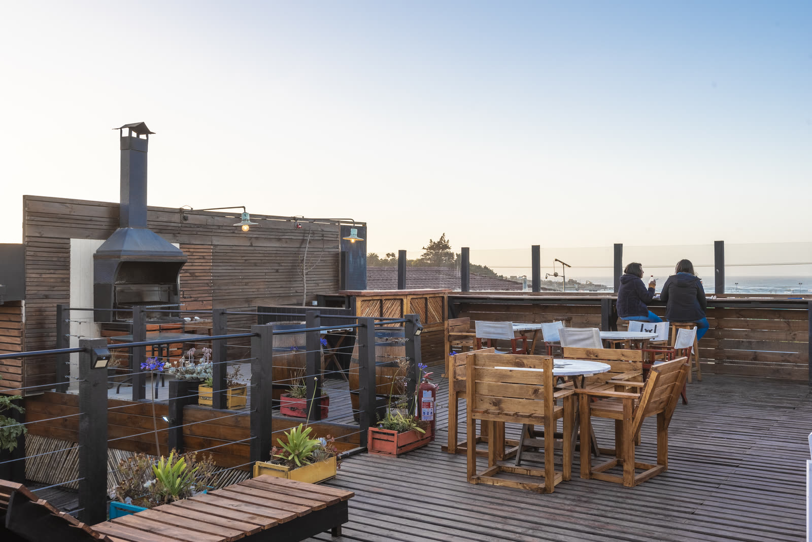 Terraza en el techo con mesas de madera y vista al océano